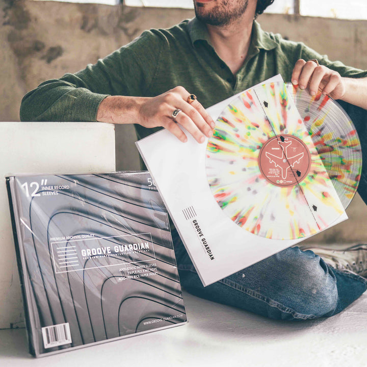 A person sitting on the floor holds a colorful splatter vinyl record and its sleeve. Next to them is a pack of Groove Guardian Premium 12" LP Inner Record Sleeves, containing 12 archival-quality, anti-static sleeves designed to provide superior protection for cherished vinyl collections.