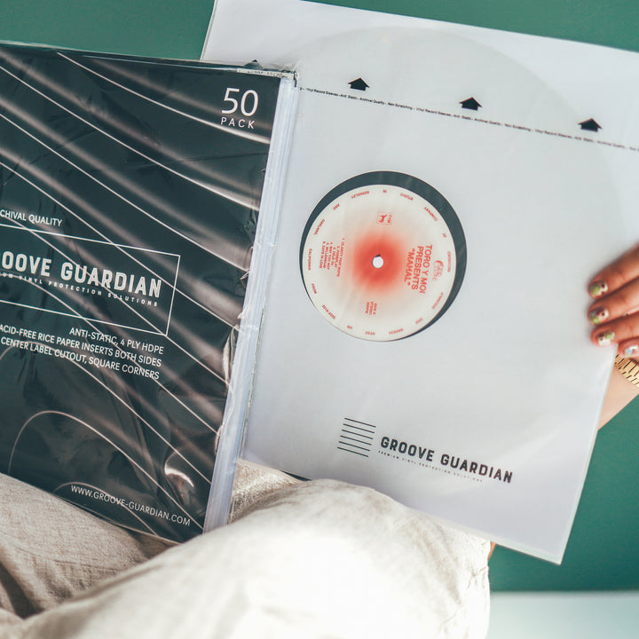 A hand holds a Groove Guardian Ultra-Premium 12" LP Inner Record Sleeve alongside a vinyl record. The setting is bright and modern, showcasing the sleek packaging and high-quality album sleeves from Groove Guardian.