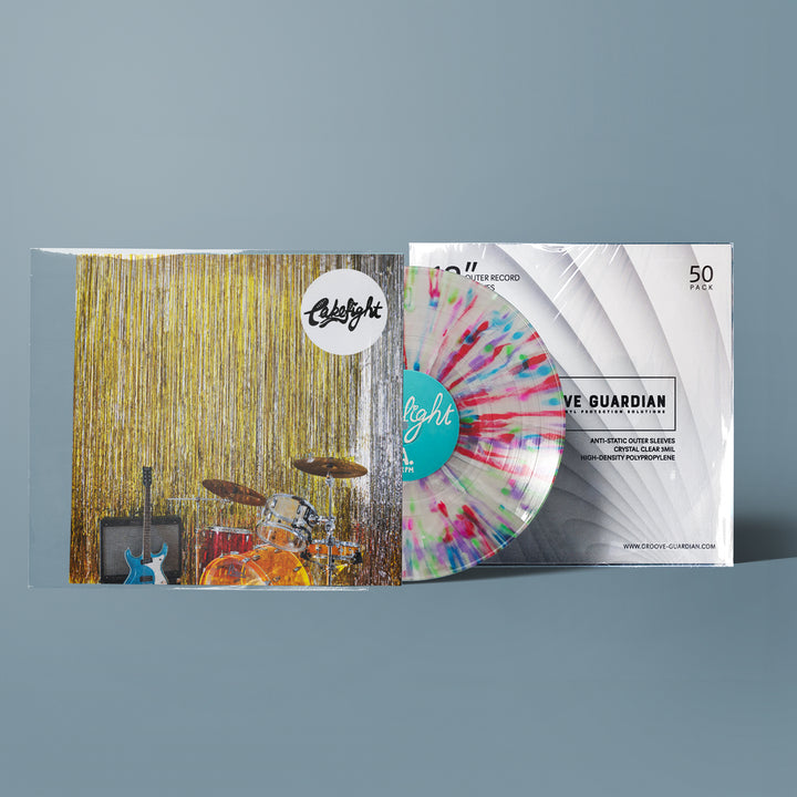 A vibrant vinyl record, partially out of its sleeve, rests next to a cover that showcases a drum set, guitars, and a gold tinsel backdrop. The clear record, flecked with blue, pink, and yellow splatters, makes for an eye-catching companion to Groove Guardian’s Premium 12" LP Outer Record Sleeves.